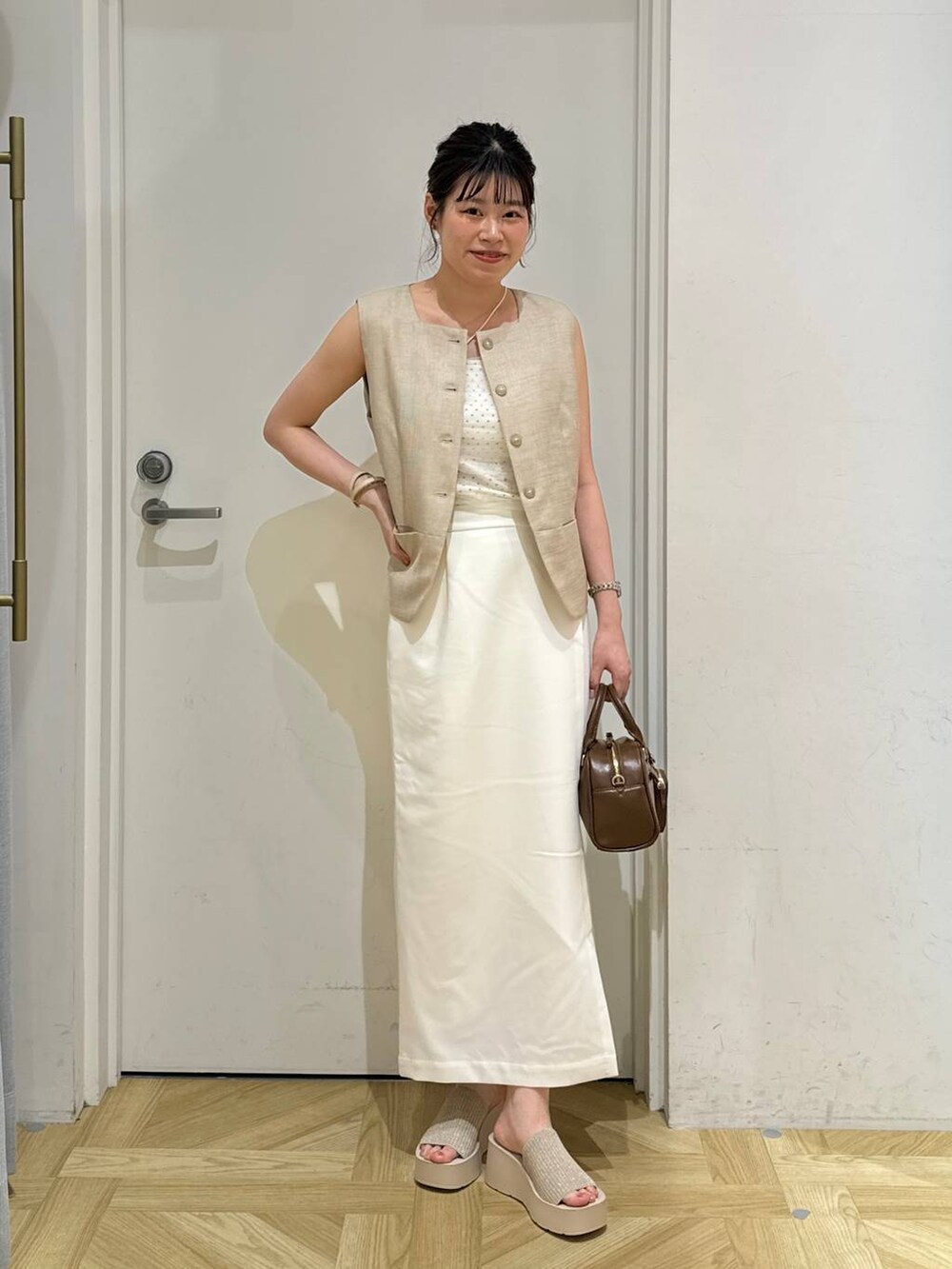ホワイト系のサンダル、ベージュ系のブルゾン、ホワイト系のスカートを着用したレディースの夏コーディネートの2枚目の写真