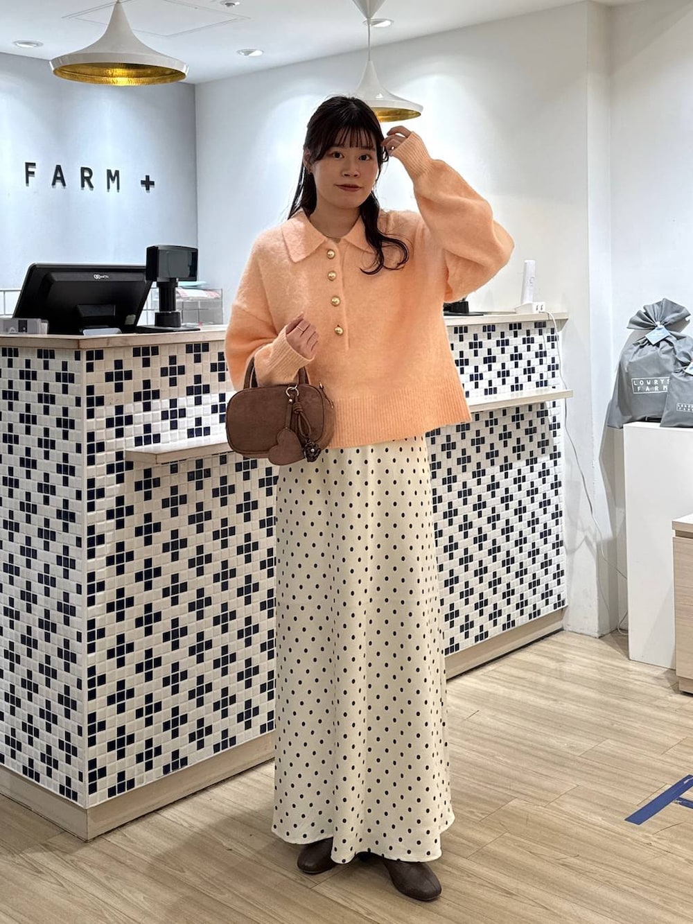 ホワイト系のスカート、ブラウン系のボストンバッグ、ブラウン系のブーツを着用したレディースの冬コーディネートの3枚目の写真