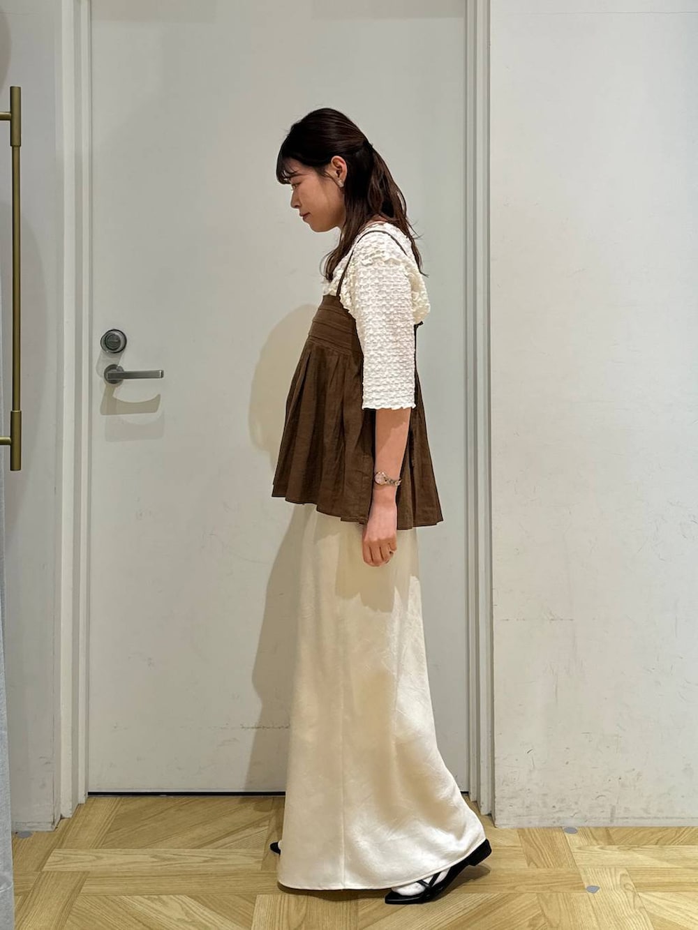 ブラウン系のキャミソール、ブラック系のサンダル、ホワイト系のスカートを着用したレディースの春コーディネートの4枚目の写真