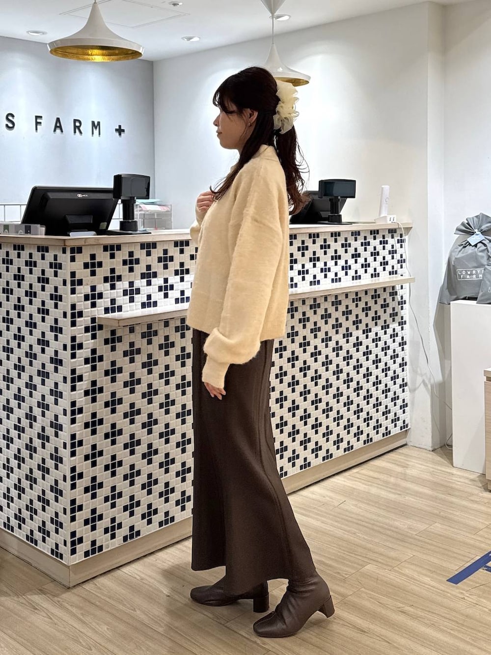 ブラウン系のスカート、ブラウン系のブーツ、ホワイト系のニット/セーターを着用したレディースの冬コーディネートの4枚目の写真