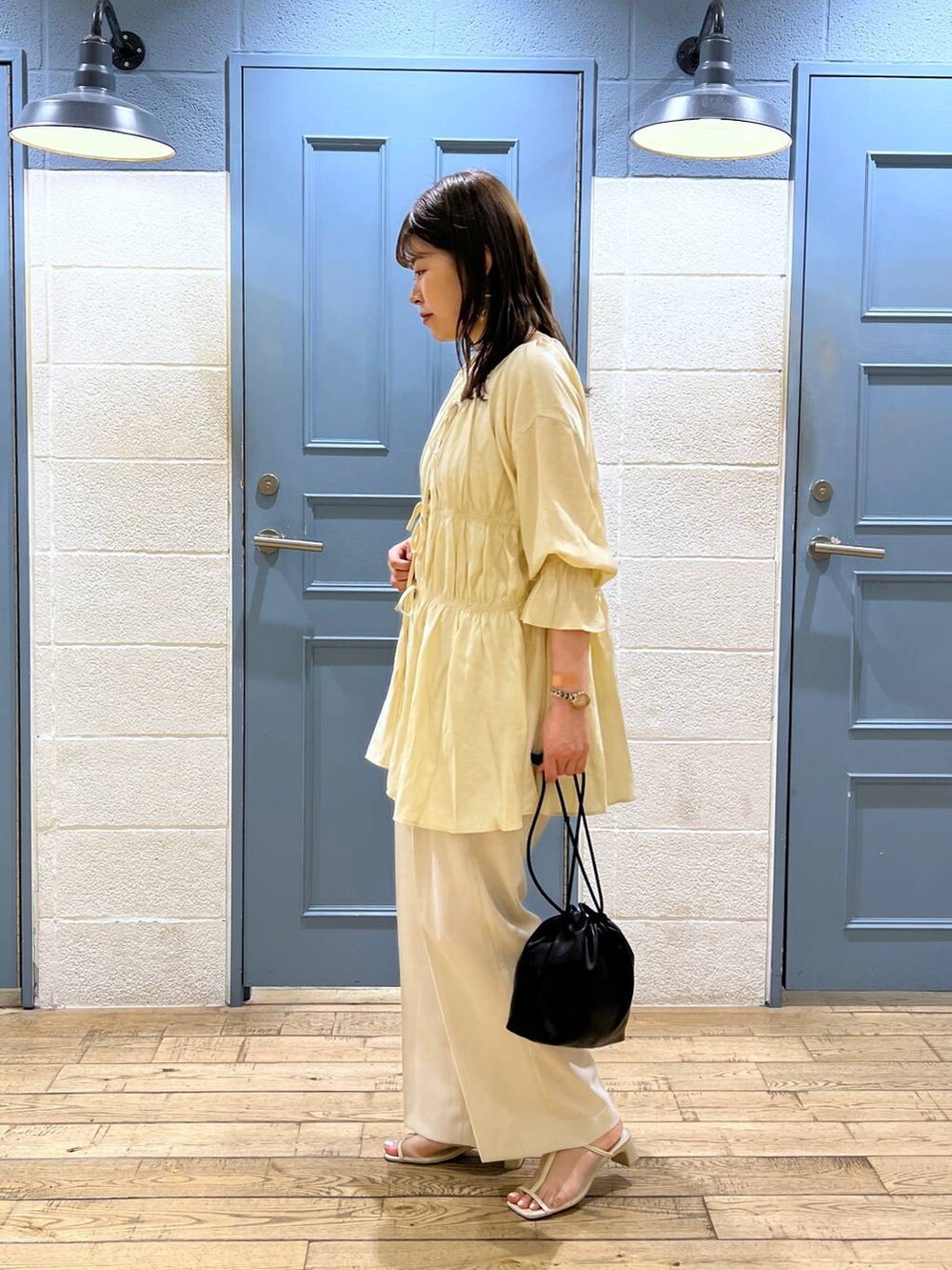 ベージュ系のシャツ/ブラウス、ホワイト系のスラックス、ホワイト系のサンダルを着用したレディースの夏コーディネートの2枚目の写真