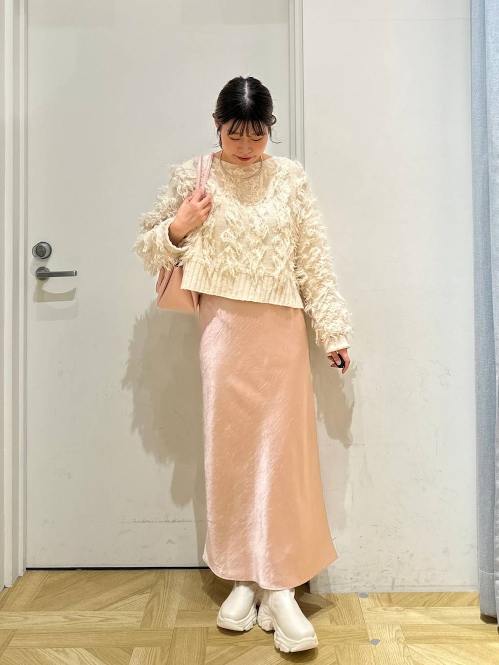 ホワイト系のブルゾン、ピンク系のショルダーバッグ、ホワイト系のブーツを着用したレディースの冬コーディネートの5枚目の写真