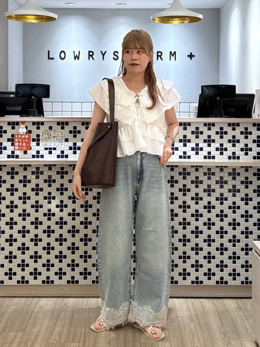 ブルー系のデニムパンツ、ホワイト系のサンダル、ブラウン系のトートバッグを着用したレディースの夏コーディネートの3枚目の写真