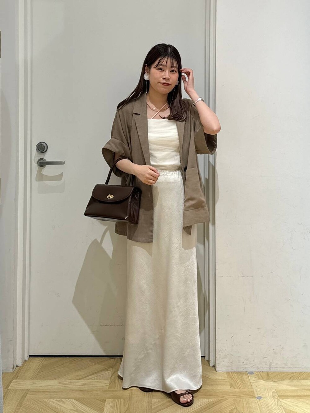 ブラウン系のスカート、ベージュ系のテーラードジャケット、ブラウン系のサンダルを着用したレディースの夏コーディネートの2枚目の写真