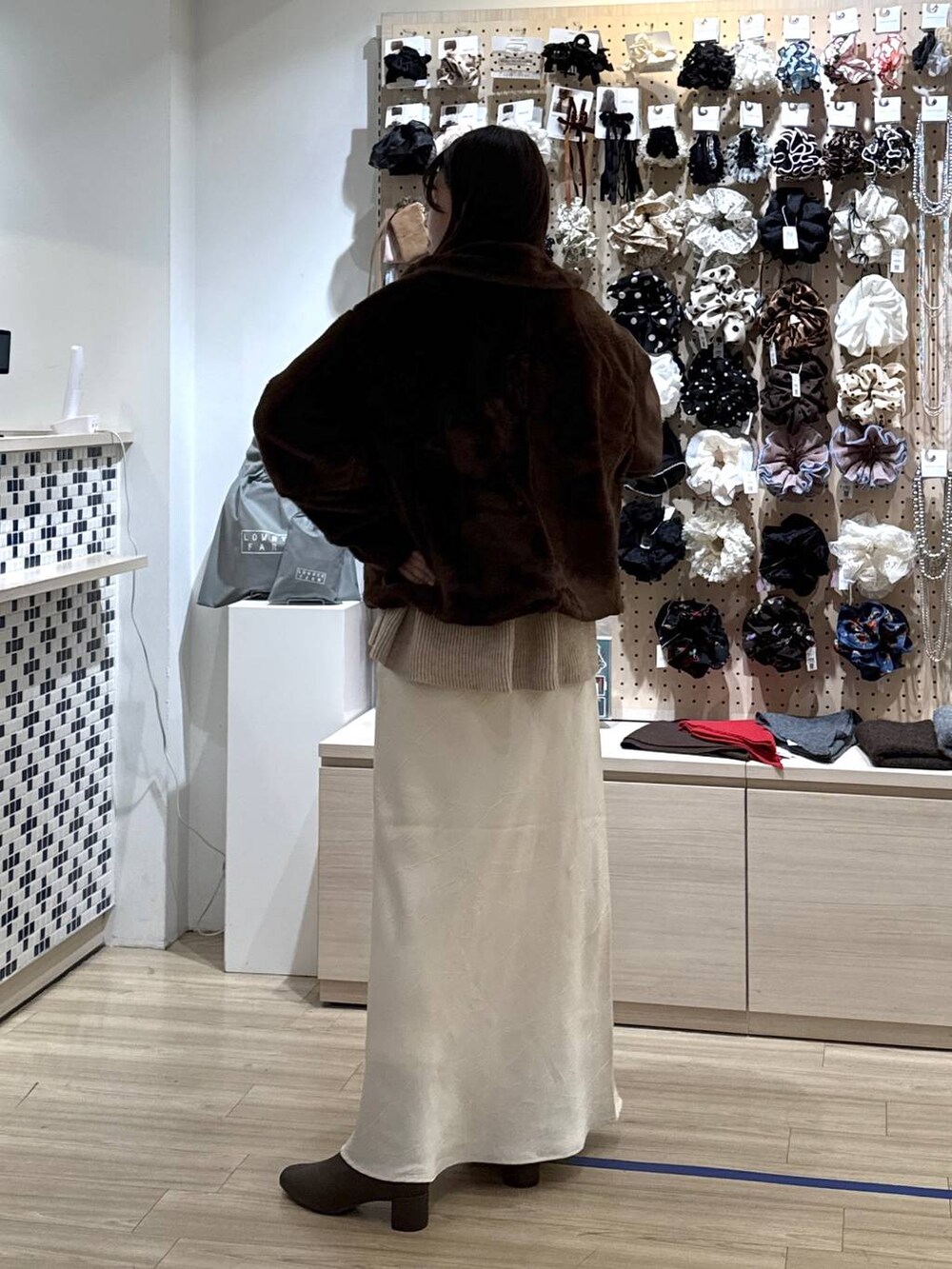 ホワイト系のスカート、ブラウン系のブルゾン、ベージュ系のカーディガン/ボレロを着用したレディースの冬コーディネートの5枚目の写真