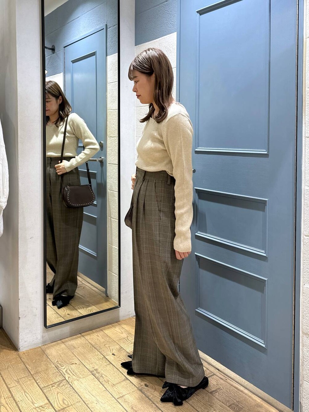 ブラック系のパンプス、ブラウン系のショルダーバッグ、ブラウン系のスラックスを着用したレディースの秋コーディネートの2枚目の写真