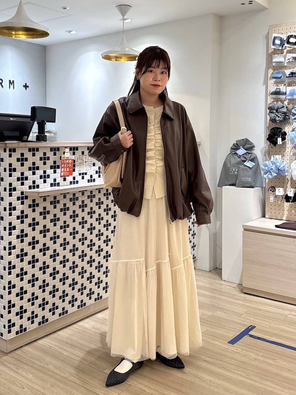 ブラック系のパンプス、ベージュ系のショルダーバッグ、ホワイト系のブルゾンを着用したレディースの春コーディネートの2枚目の写真