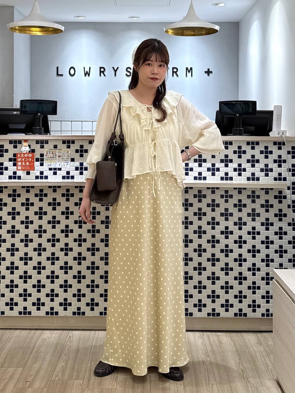 ホワイト系のスカート、ブラウン系のローファー、ホワイト系のタンクトップを着用したレディースの春コーディネートの2枚目の写真