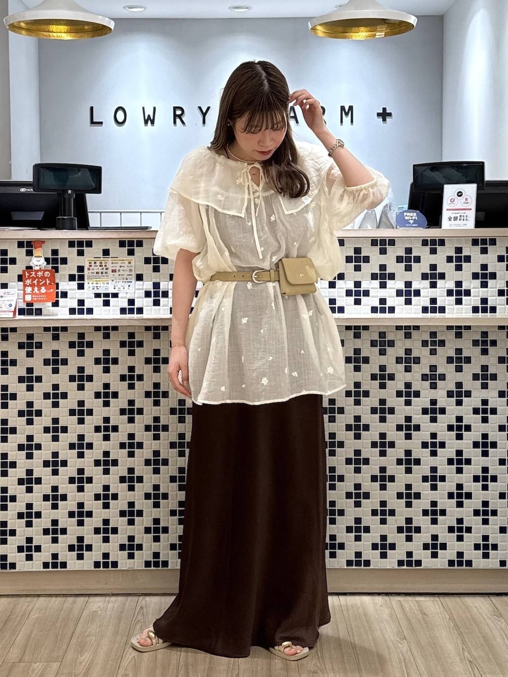 ホワイト系のワンピース、ブラウン系のスカート、ホワイト系のサンダルを着用したレディースの夏コーディネートの3枚目の写真