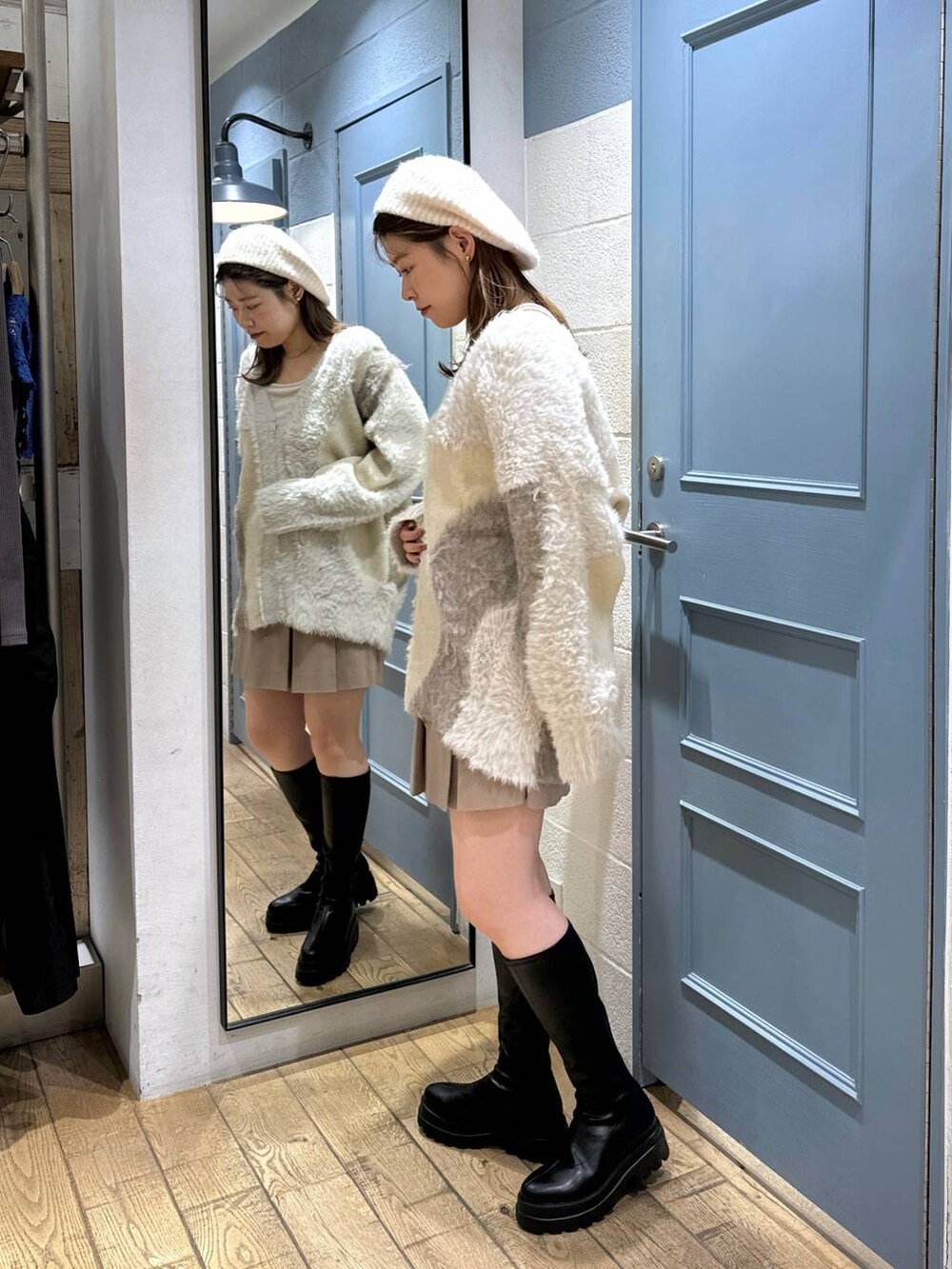 ベージュ系のスカート、ブラック系のブーツ、ホワイト系のキャミソールを着用したレディースの秋コーディネートの3枚目の写真