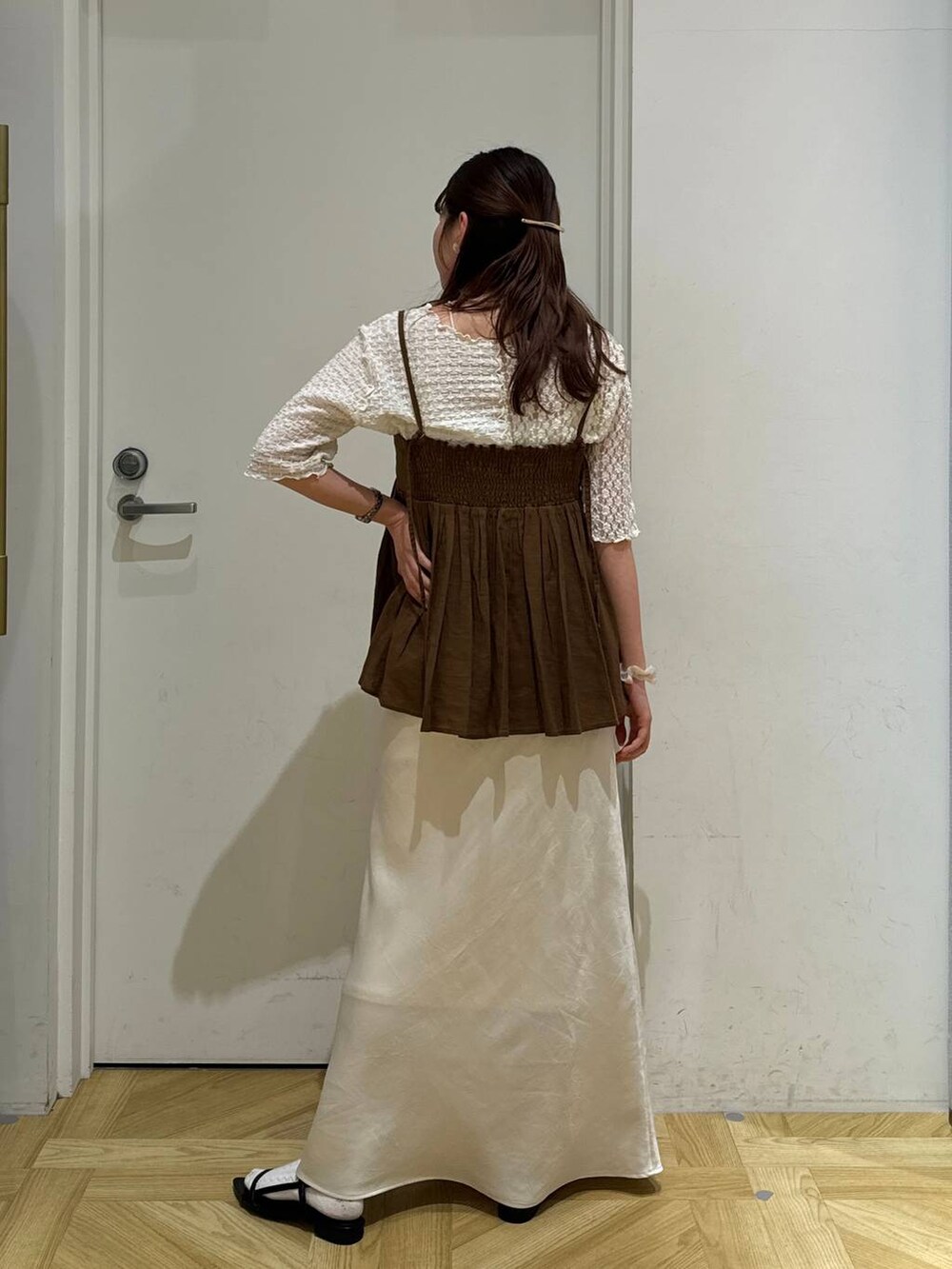 ブラウン系のキャミソール、ブラック系のサンダル、ホワイト系のスカートを着用したレディースの春コーディネートの5枚目の写真