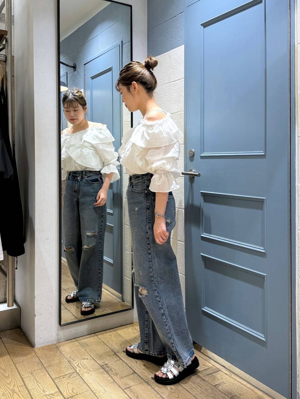 シルバー系のスニーカー、ホワイト系のシャツ/ブラウス、ブルー系のデニムパンツを着用したレディースの夏コーディネートの2枚目の写真