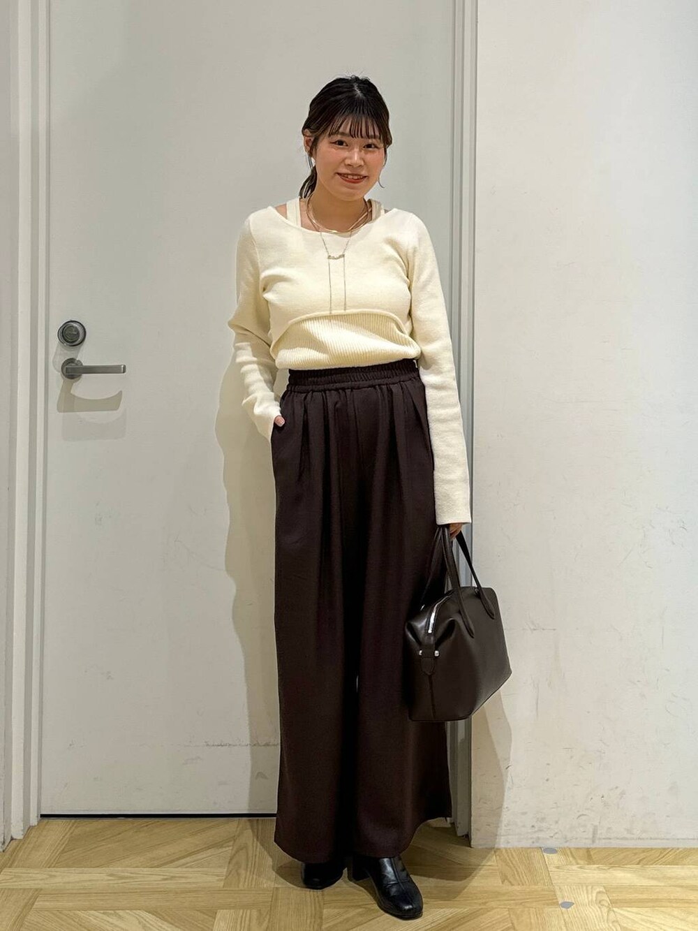 ブラック系のブーツ、ブラウン系のショルダーバッグ、ホワイト系のブルゾンを着用したレディースの冬コーディネートの6枚目の写真