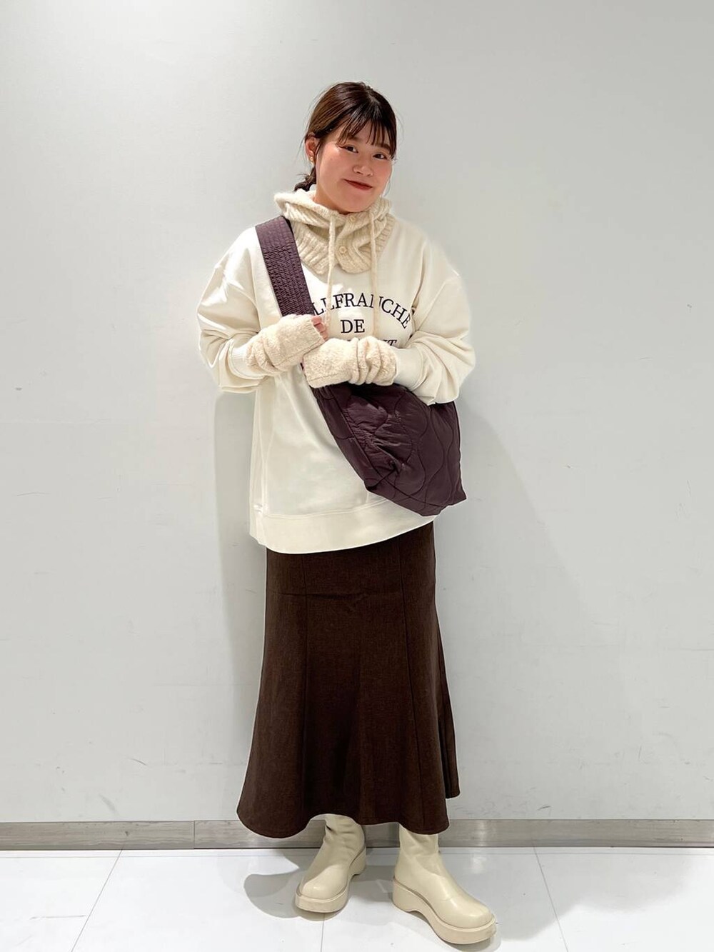 ホワイト系のスウェット、ホワイト系のブーツ、ブラウン系のスカートを着用したレディースの秋コーディネートの2枚目の写真