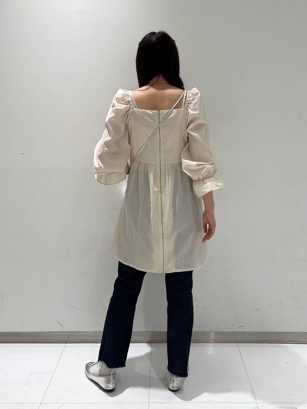 シルバー系のショルダーバッグ、グレー系のバレエシューズ、ブルー系のデニムパンツを着用したレディースの冬コーディネートの4枚目の写真