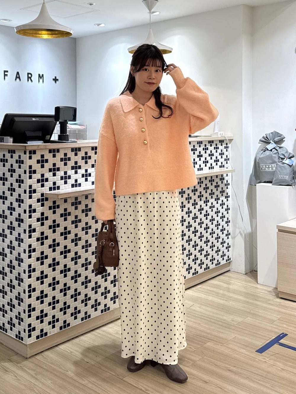 ホワイト系のスカート、ブラウン系のボストンバッグ、ブラウン系のブーツを着用したレディースの冬コーディネートの6枚目の写真