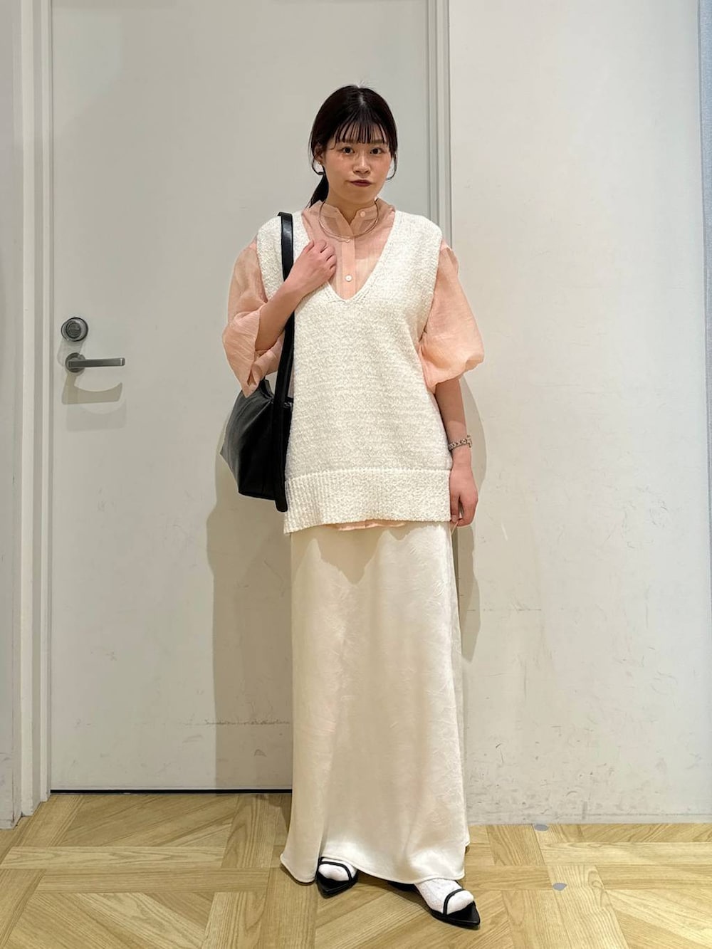 ブラック系のサンダル、ホワイト系のニット/セーター、ブラック系のショルダーバッグを着用したレディースの春コーディネートの2枚目の写真