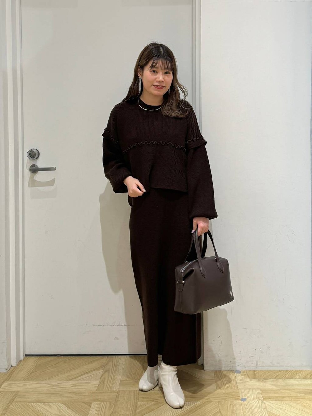 ホワイト系のブーツ、ブラウン系のショルダーバッグ、ブラウン系のワンピースを着用したレディースの冬コーディネートの6枚目の写真