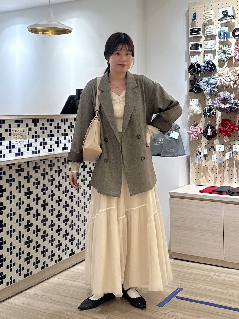 ブラック系のパンプス、ブラウン系のテーラードジャケット、ベージュ系のショルダーバッグを着用したレディースの春コーディネートの2枚目の写真