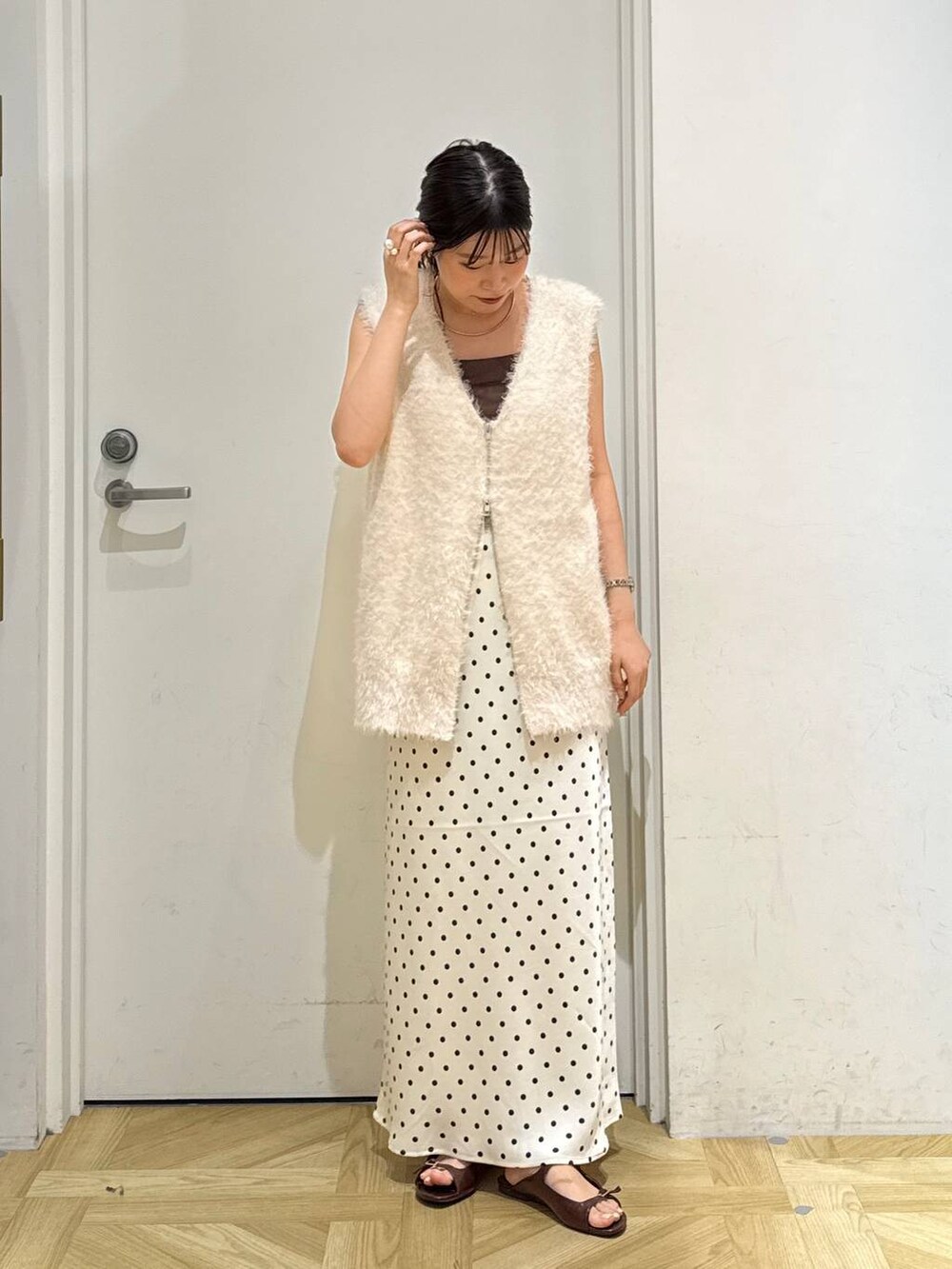 ホワイト系のスカート、ブラウン系のサンダル、ホワイト系のベストを着用したレディースの夏コーディネートの2枚目の写真