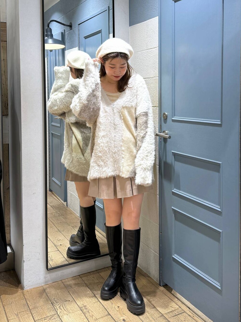 ベージュ系のスカート、ブラック系のブーツ、ホワイト系のキャミソールを着用したレディースの秋コーディネートの2枚目の写真