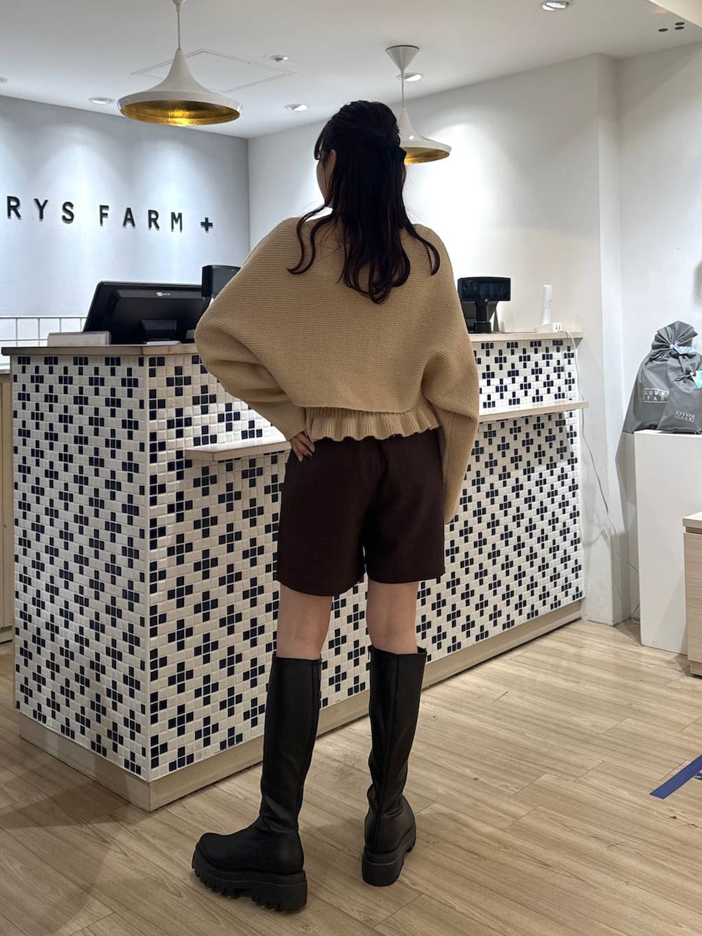 ブラウン系のステンカラーコート、ブラウン系のその他パンツ、ブラック系のブーツを着用したレディースの秋コーディネートの8枚目の写真