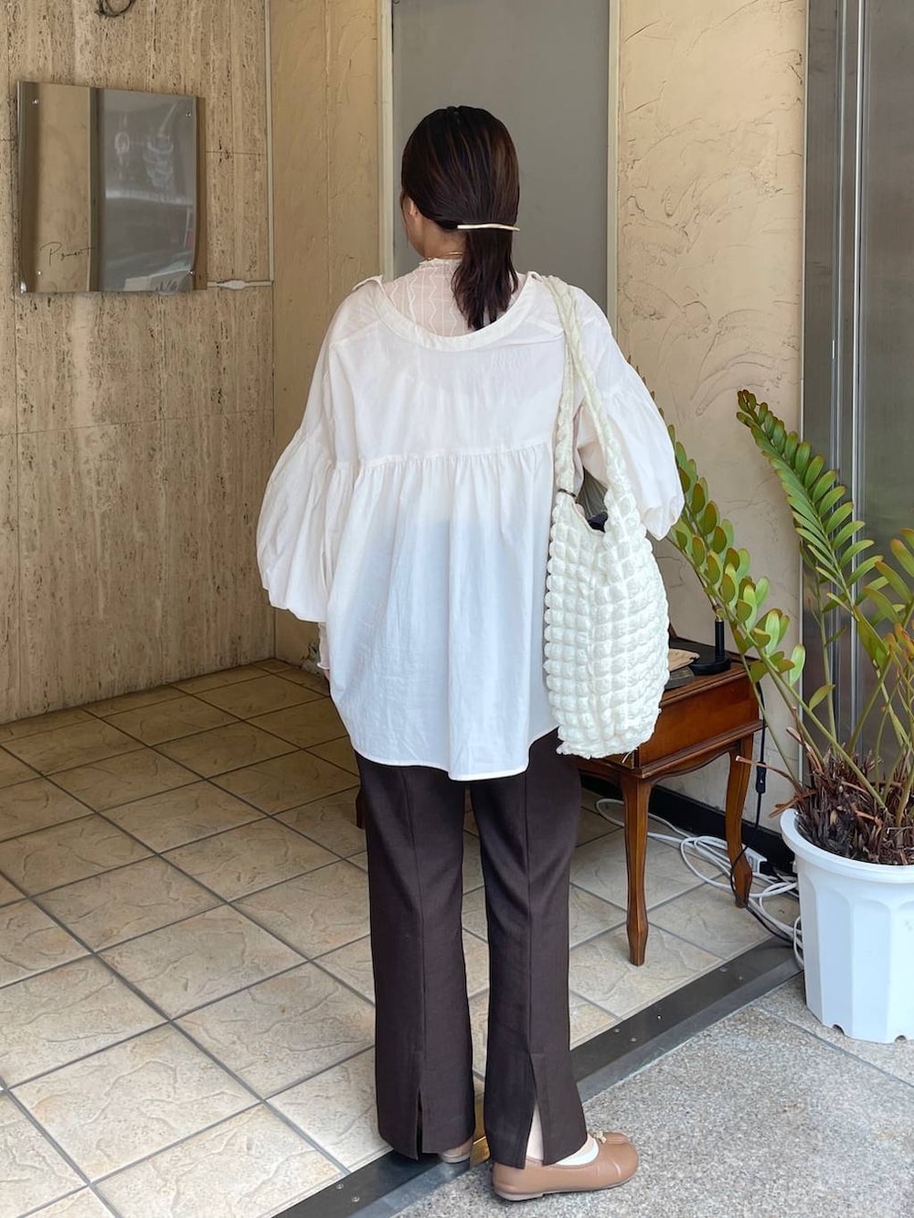 ホワイト系のショルダーバッグ、ホワイト系のTシャツ/カットソー、ブラウン系のスラックスを着用したレディースの秋コーディネートの4枚目の写真
