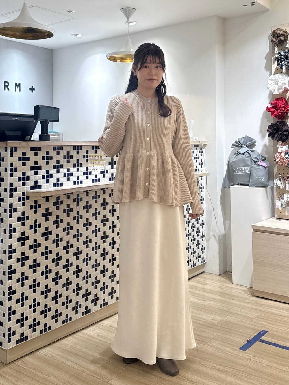 ホワイト系のスカート、ベージュ系のカーディガン/ボレロ、ブラウン系のブーツを着用したレディースの冬コーディネートの5枚目の写真