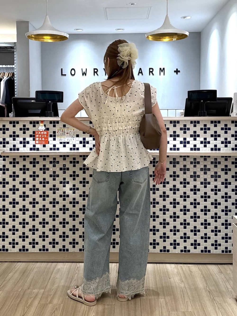 ブルー系のデニムパンツ、ホワイト系のサンダル、ブラウン系のショルダーバッグを着用したレディースの夏コーディネートの5枚目の写真