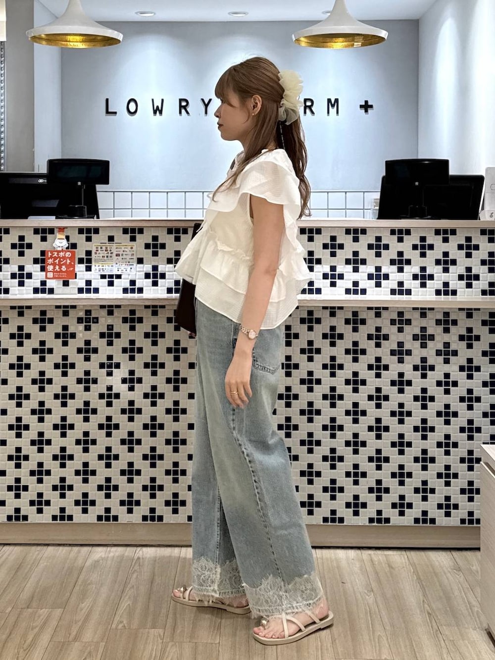 ブルー系のデニムパンツ、ホワイト系のサンダル、ブラウン系のトートバッグを着用したレディースの夏コーディネートの6枚目の写真