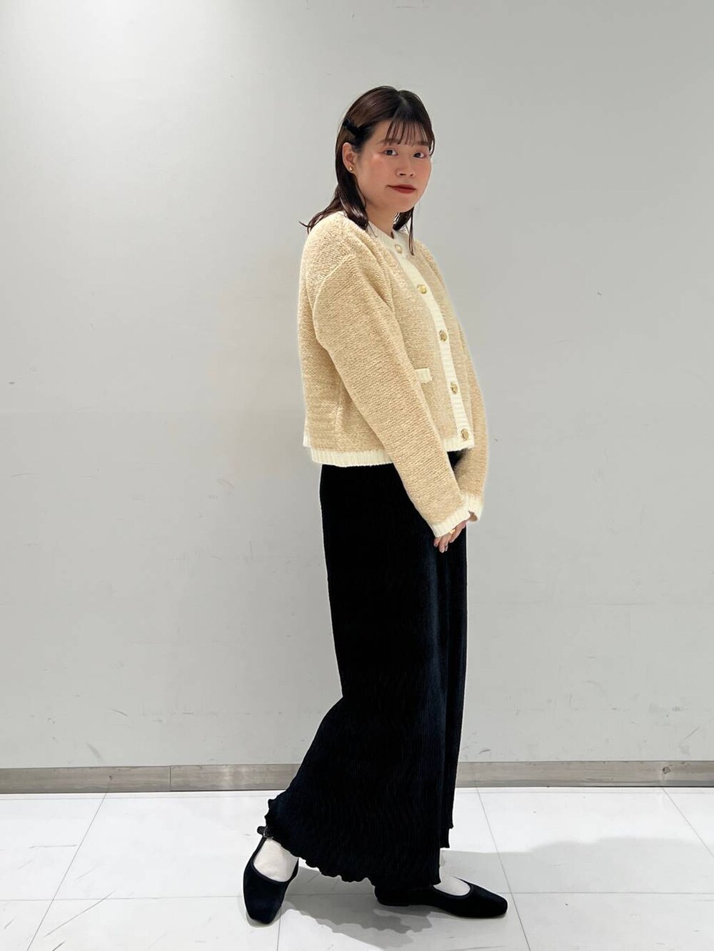 その他のパンプス、ホワイト系のカーディガン/ボレロ、ブラック系のスカートを着用したレディースの秋コーディネートの2枚目の写真