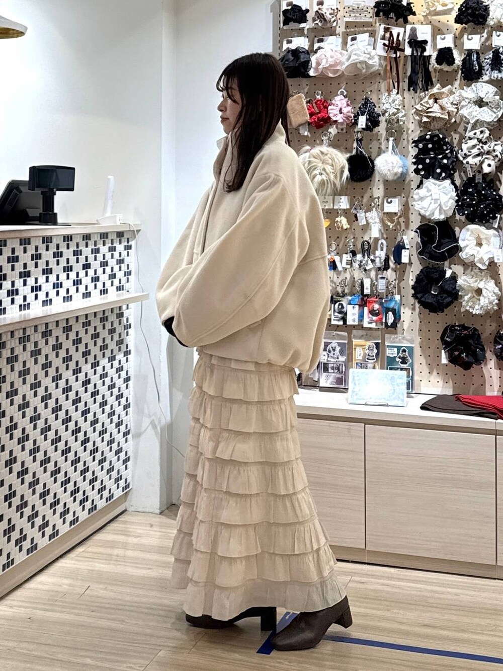 ホワイト系のブルゾン、ホワイト系のスカート、ブラウン系のポロシャツを着用したレディースの秋コーディネートの4枚目の写真