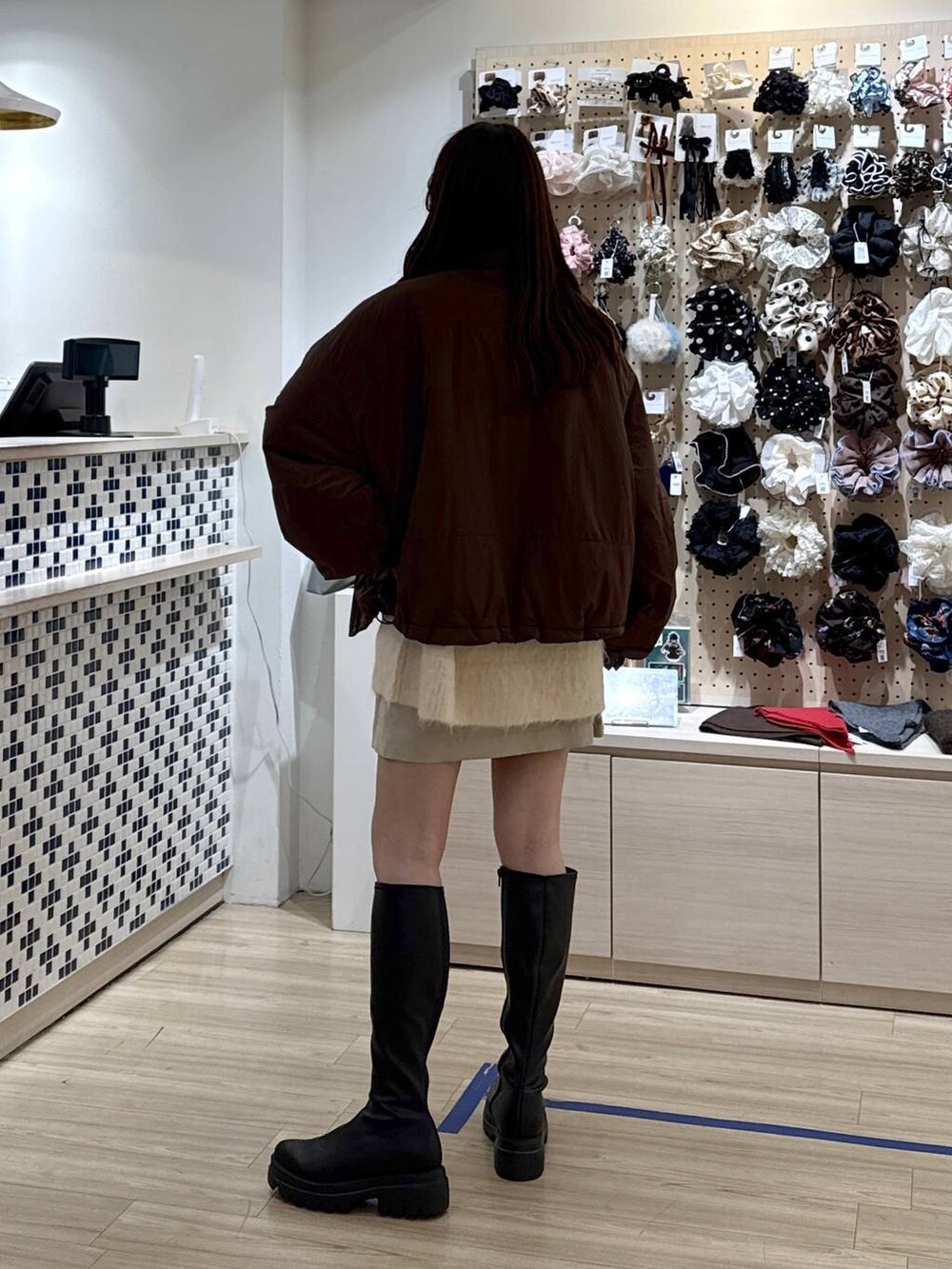 ブラウン系のその他アウター、ホワイト系のスカート、ブラック系のブーツを着用したレディースの秋コーディネートの4枚目の写真