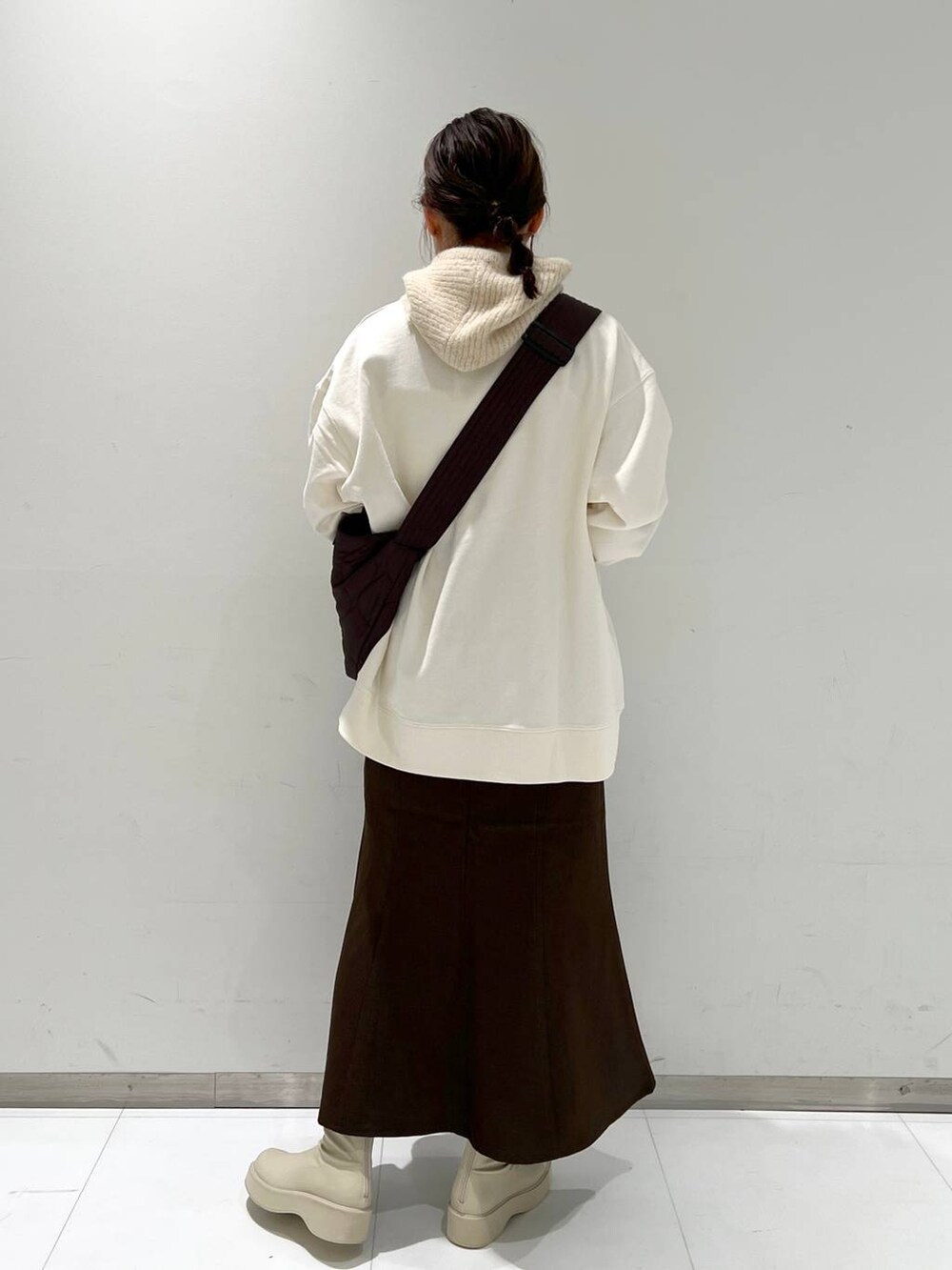 ホワイト系のスウェット、ホワイト系のブーツ、ブラウン系のスカートを着用したレディースの秋コーディネートの4枚目の写真