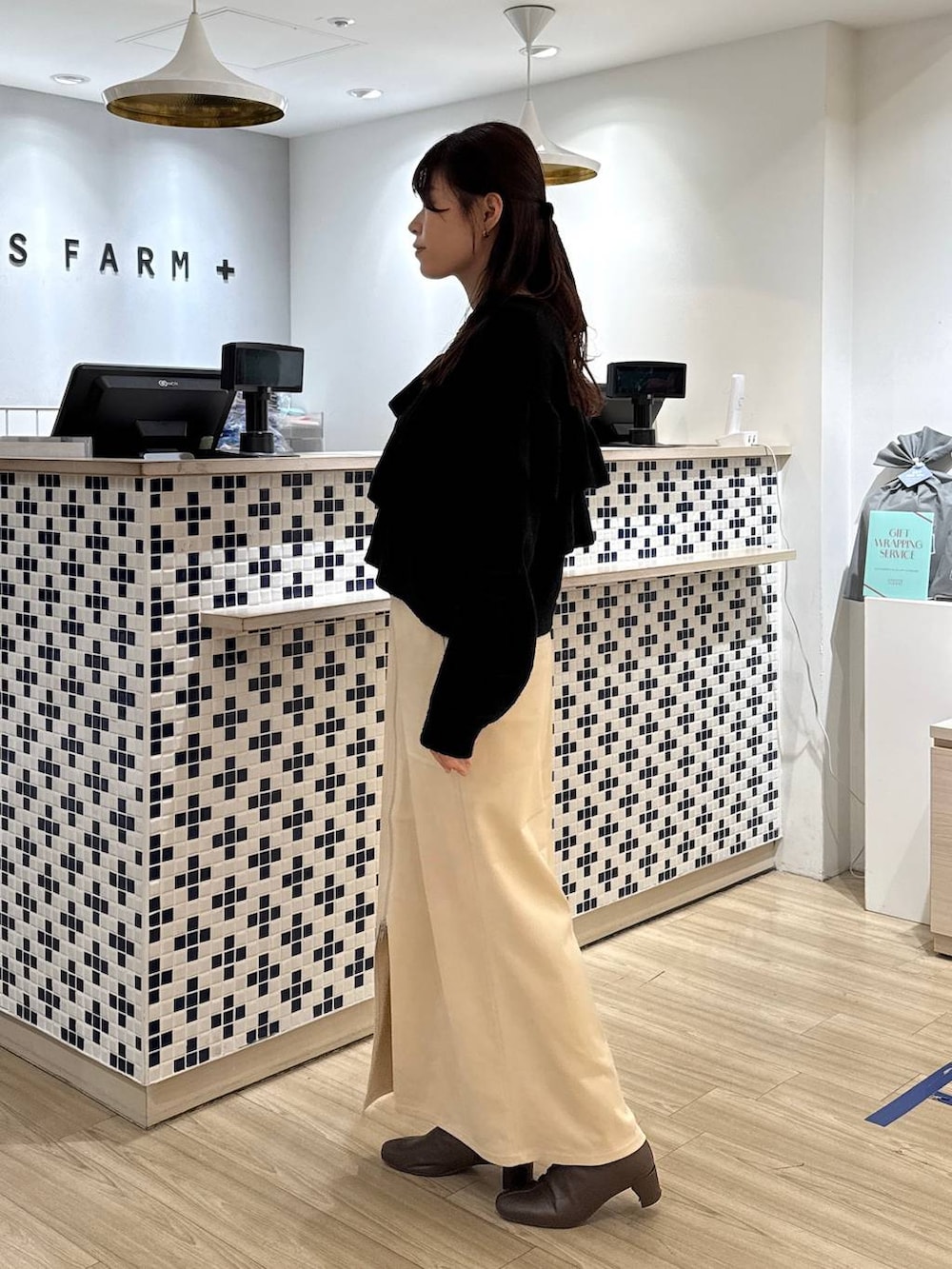 ホワイト系のスカート、ブラウン系のブーツ、ブラウン系のショルダーバッグを着用したレディースの冬コーディネートの4枚目の写真