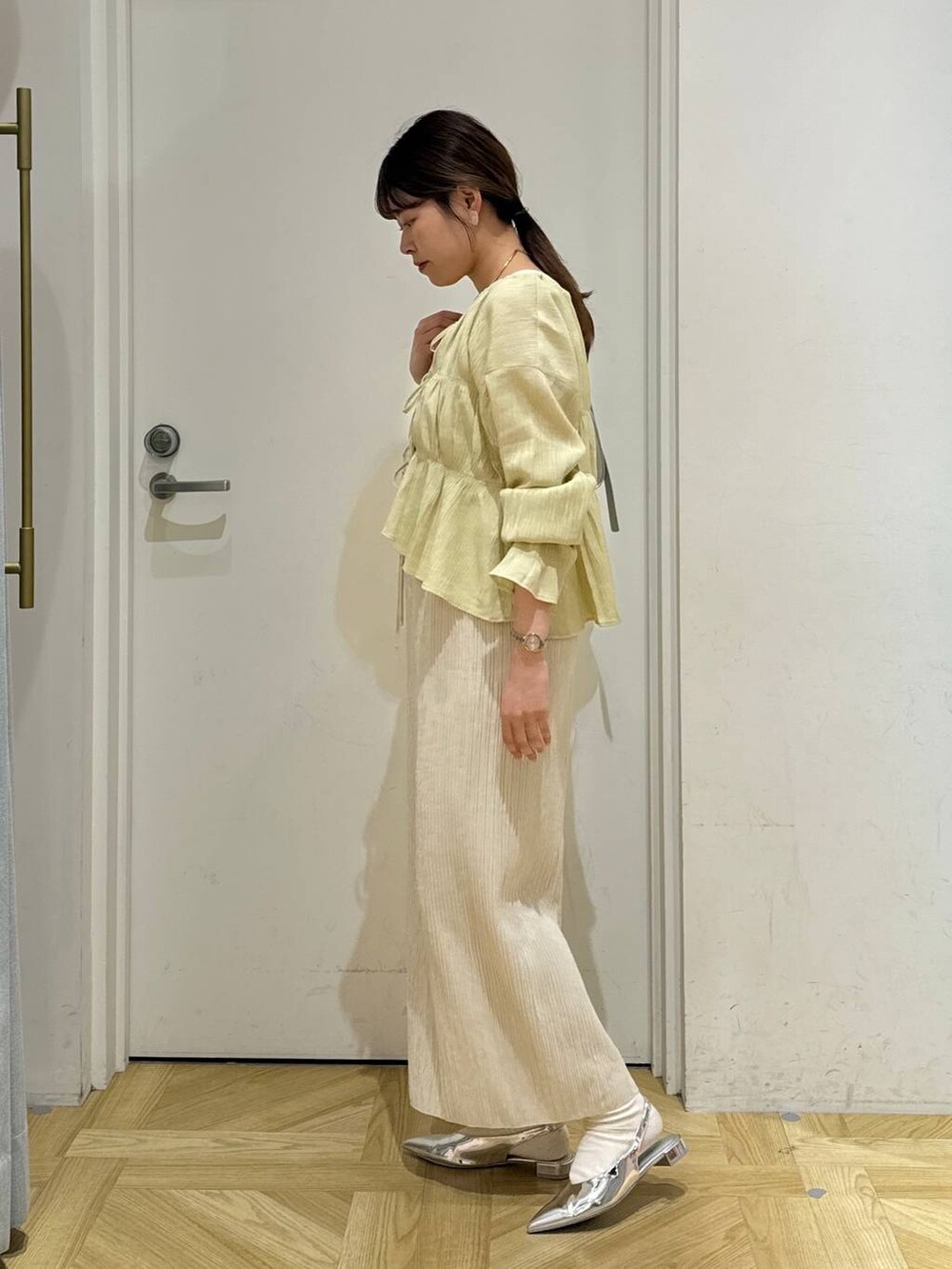 シルバー系のトートバッグ、シルバー系のパンプス、ホワイト系のスカートを着用したレディースの春コーディネートの4枚目の写真