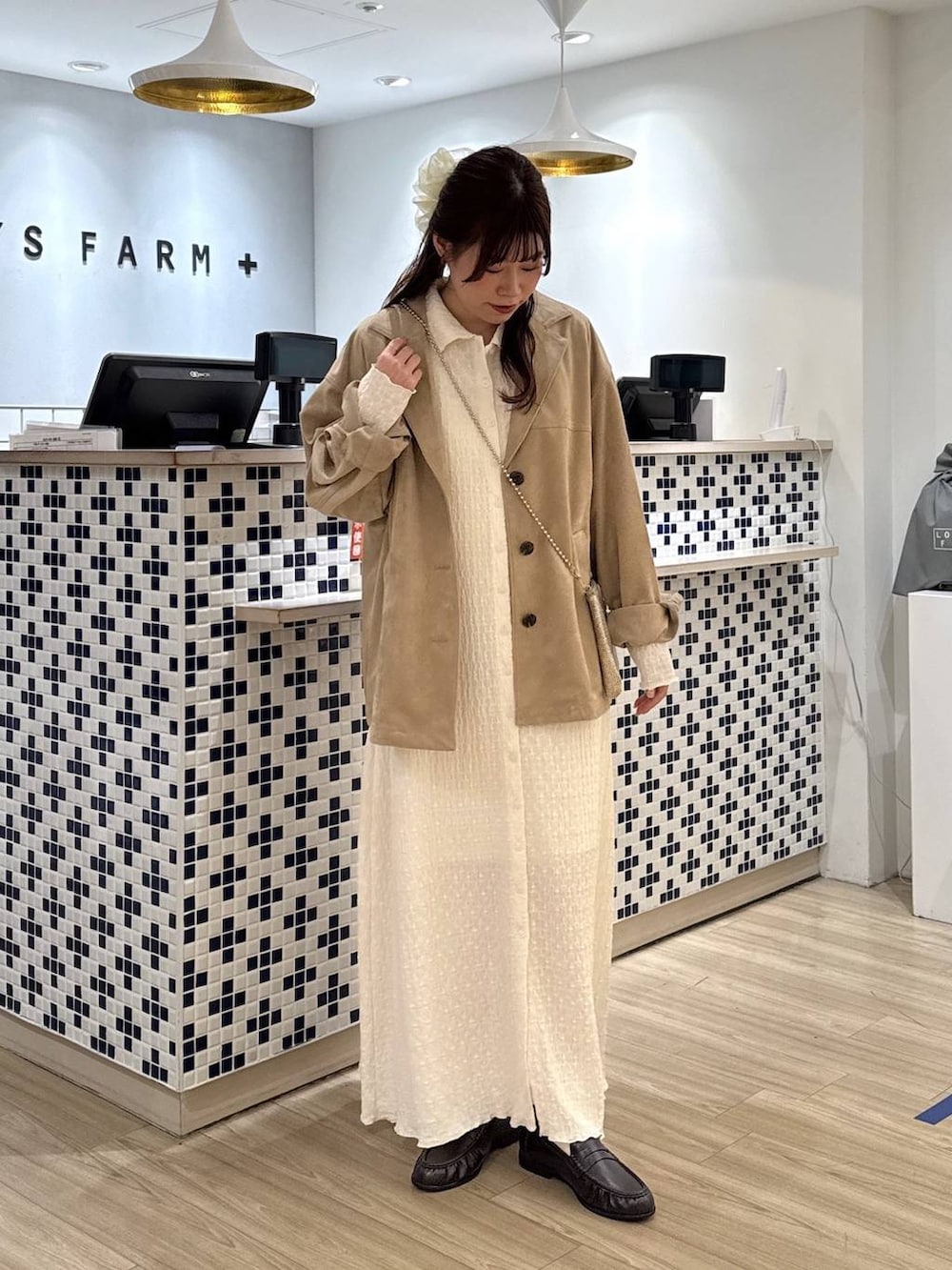 ゴールド系のショルダーバッグ、ベージュ系のテーラードジャケット、ブラウン系のローファーを着用したレディースの春コーディネートの2枚目の写真