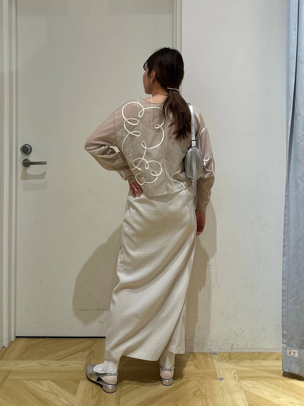 ホワイト系のスカート、ホワイト系のテーラードジャケット、シルバー系のトートバッグを着用したレディースの春コーディネートの9枚目の写真