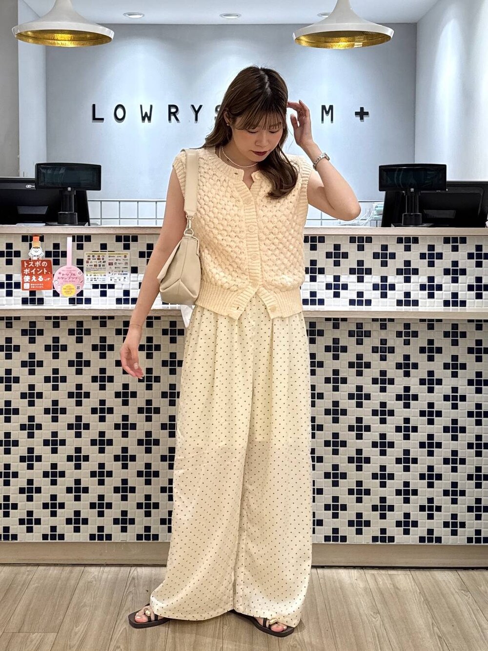 ホワイト系のベスト、ホワイト系のショルダーバッグ、ブラウン系のサンダルを着用したレディースの夏コーディネートの4枚目の写真