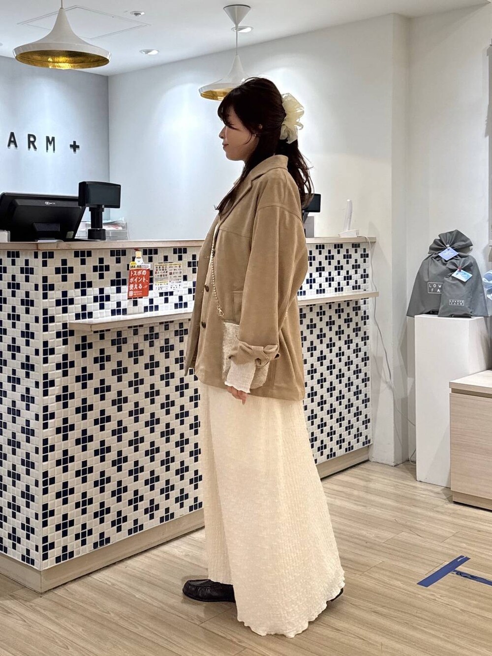 ゴールド系のショルダーバッグ、ベージュ系のテーラードジャケット、ブラウン系のローファーを着用したレディースの春コーディネートの3枚目の写真