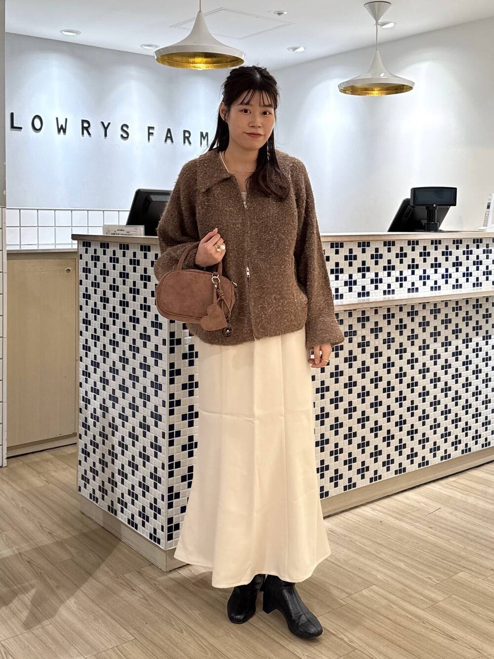 ホワイト系のスカート、ブラウン系のボストンバッグ、ブラウン系のブルゾンを着用したレディースの秋コーディネートの3枚目の写真