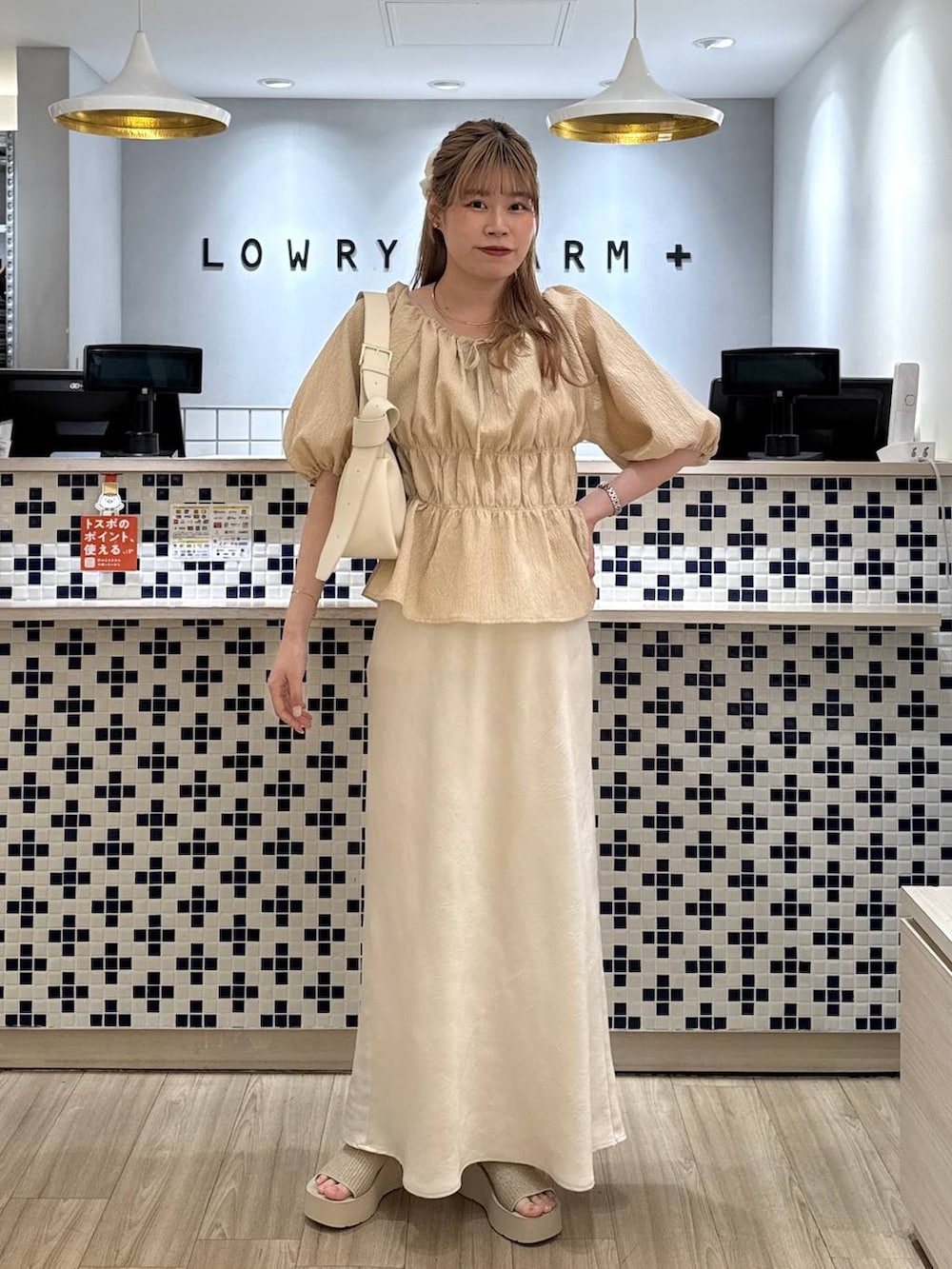 ホワイト系のスカート、ホワイト系のサンダル、ホワイト系のショルダーバッグを着用したレディースの夏コーディネートの2枚目の写真