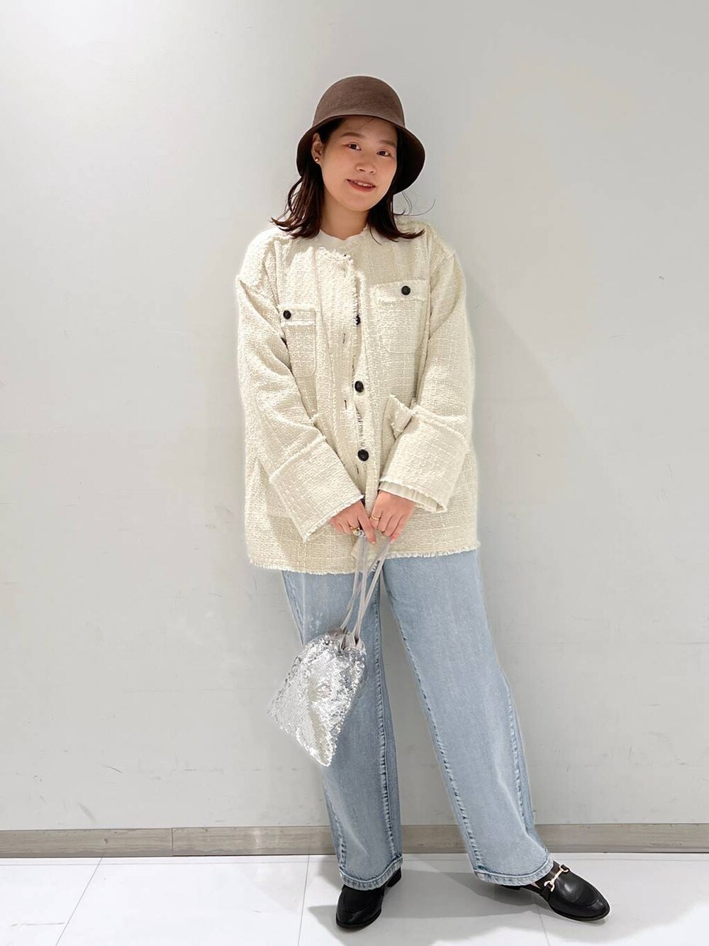 ブルー系のデニムパンツ、ブラック系のローファー、ホワイト系のノーカラージャケットを着用したレディースの秋コーディネートの3枚目の写真