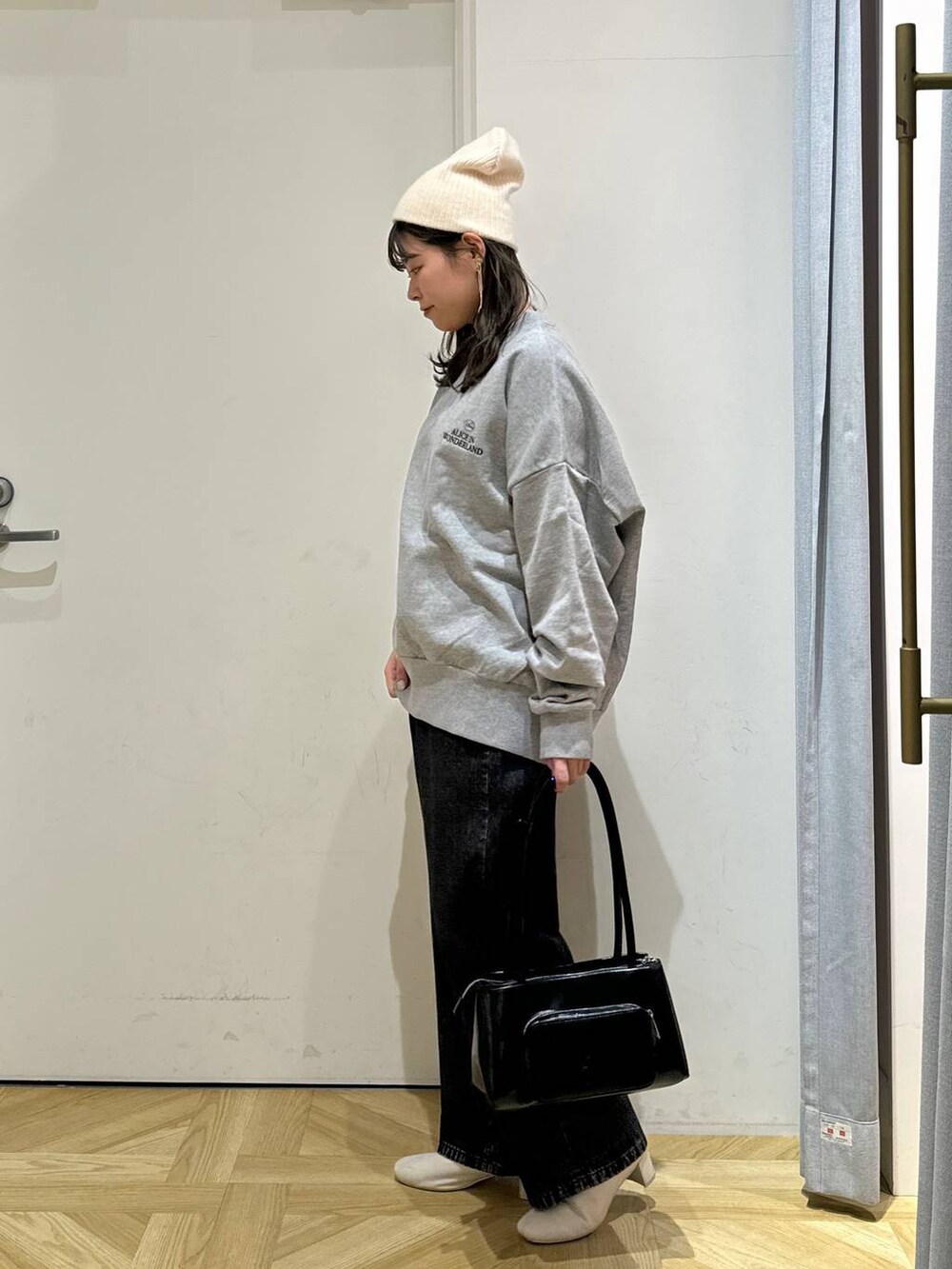 ブラック系のショルダーバッグ、ホワイト系のブーツ、グレー系のスウェットを着用したレディースの秋コーディネートの3枚目の写真
