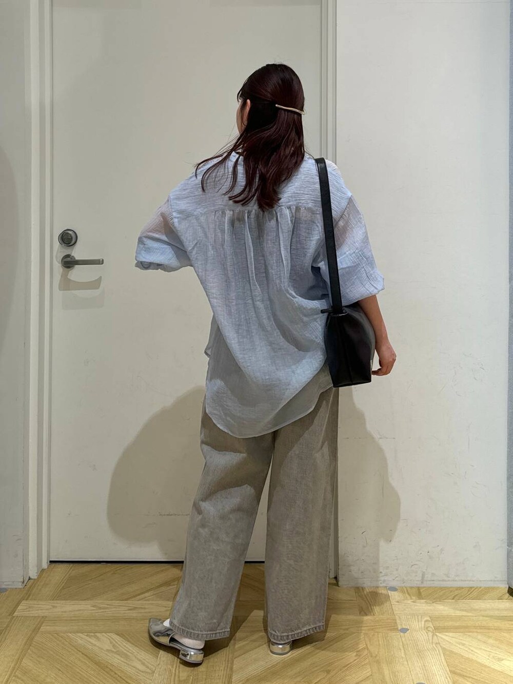 グレー系のデニムパンツ、シルバー系のパンプス、ブラック系のショルダーバッグを着用したレディースの春コーディネートの4枚目の写真