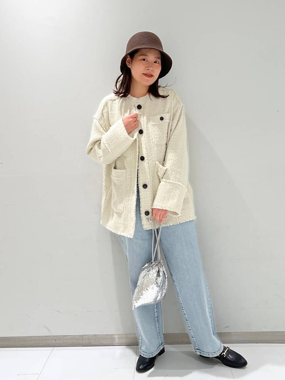 ブルー系のデニムパンツ、ブラック系のローファー、ホワイト系のノーカラージャケットを着用したレディースの秋コーディネートの2枚目の写真