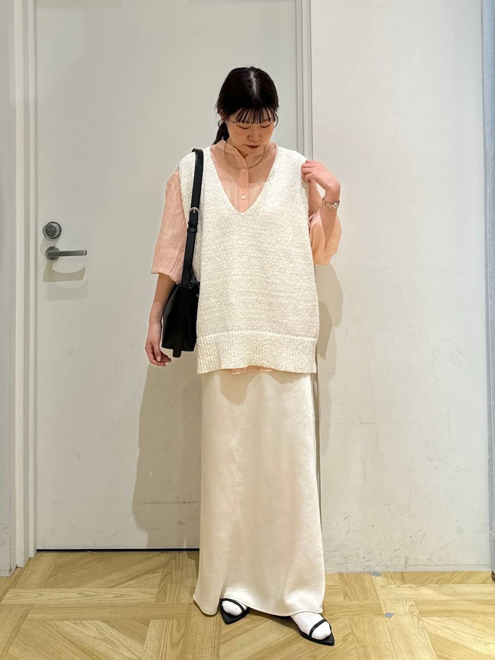 ブラック系のサンダル、ホワイト系のニット/セーター、ブラック系のショルダーバッグを着用したレディースの春コーディネートの3枚目の写真