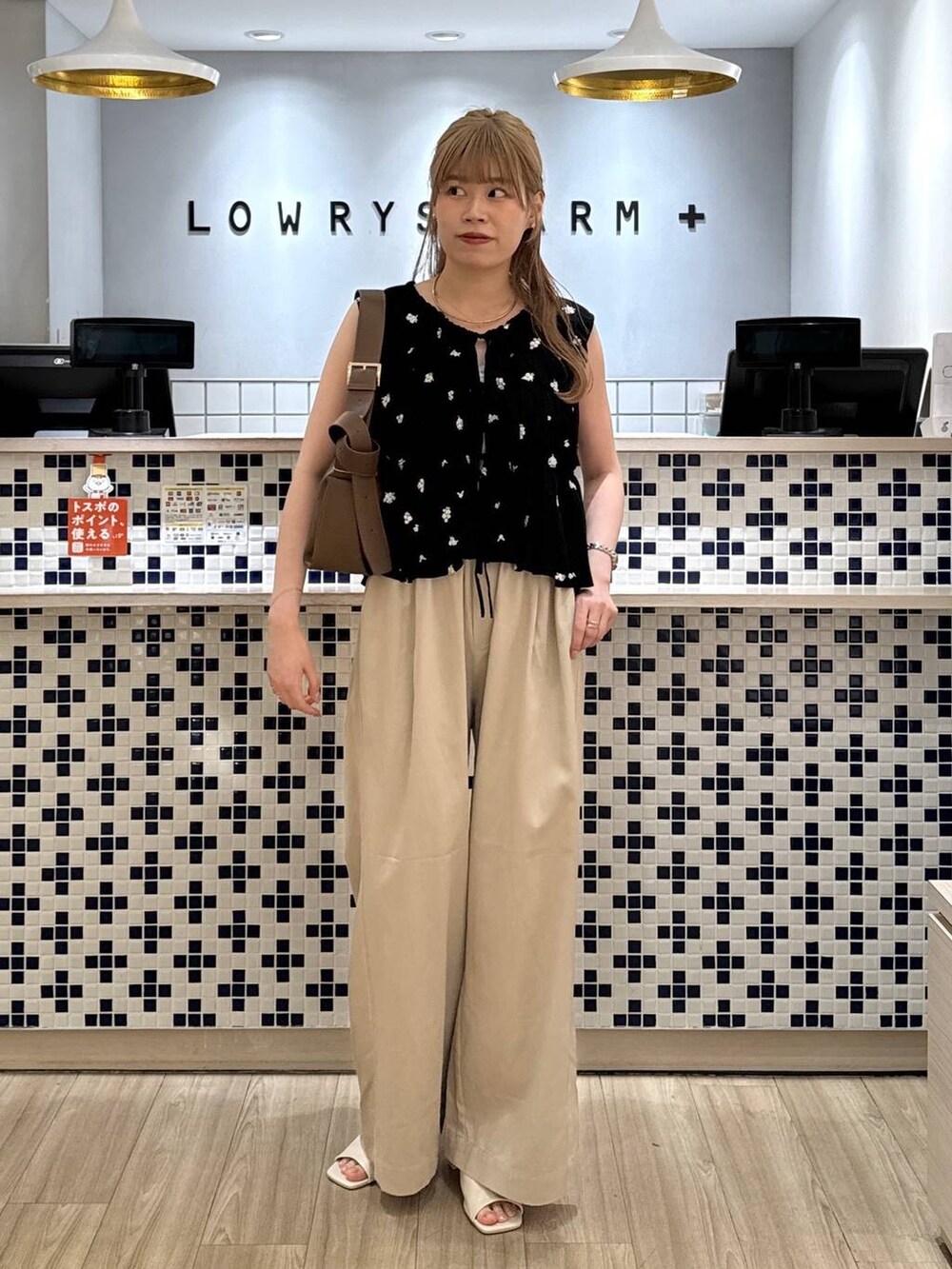 ベージュ系のデニムパンツ、ブラウン系のショルダーバッグ、ホワイト系のサンダルを着用したレディースの夏コーディネートの5枚目の写真