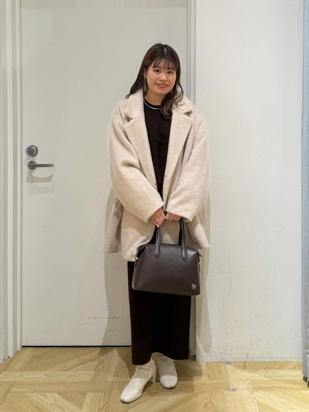 ホワイト系のブーツ、ブラウン系のショルダーバッグ、ブラウン系のワンピースを着用したレディースの冬コーディネートの3枚目の写真