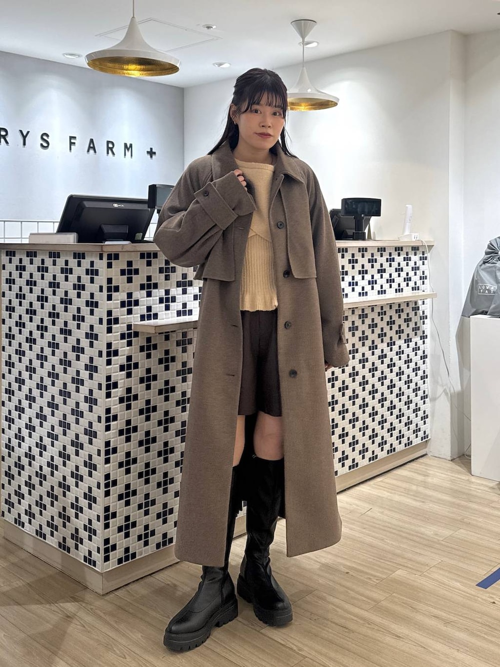 ブラウン系のステンカラーコート、ブラウン系のその他パンツ、ブラック系のブーツを着用したレディースの秋コーディネートの2枚目の写真